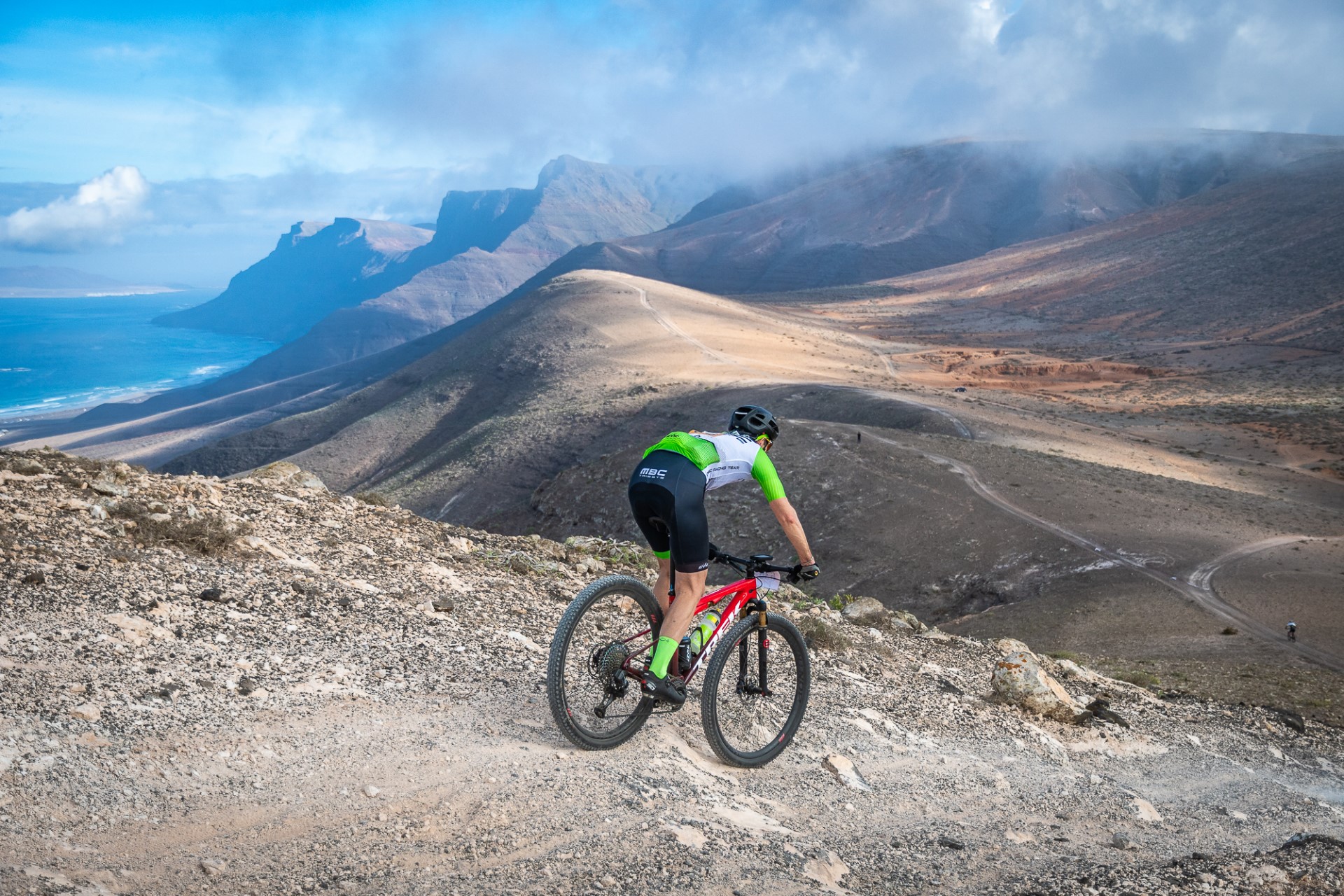 Ciclista mujer montando en bicicleta en un sendero de montaña ciclista mujer  con casco y gafas montando en bicicleta de montaña en el sendero rocoso de  verano